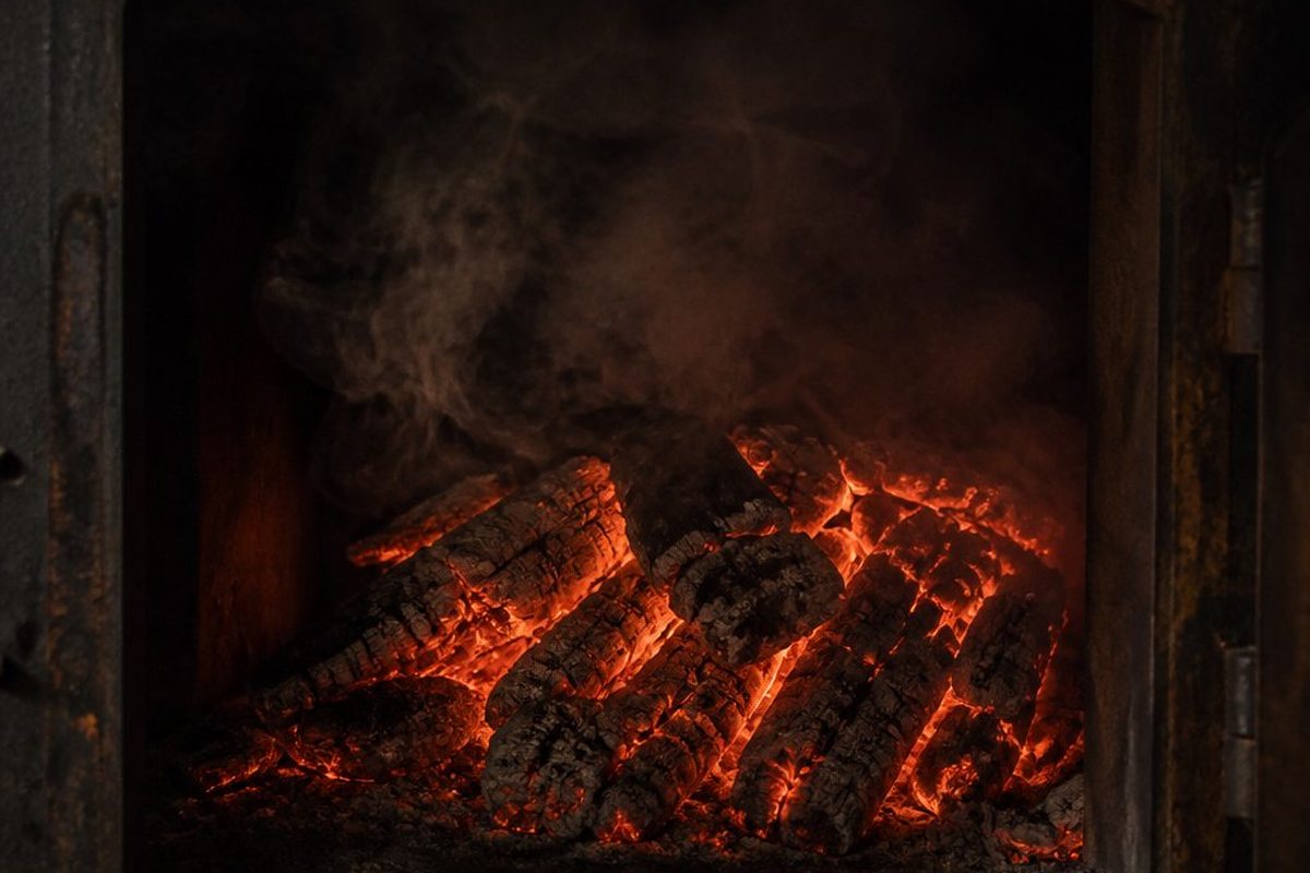 A bed of glowing orange post oak coals with grey ash edges